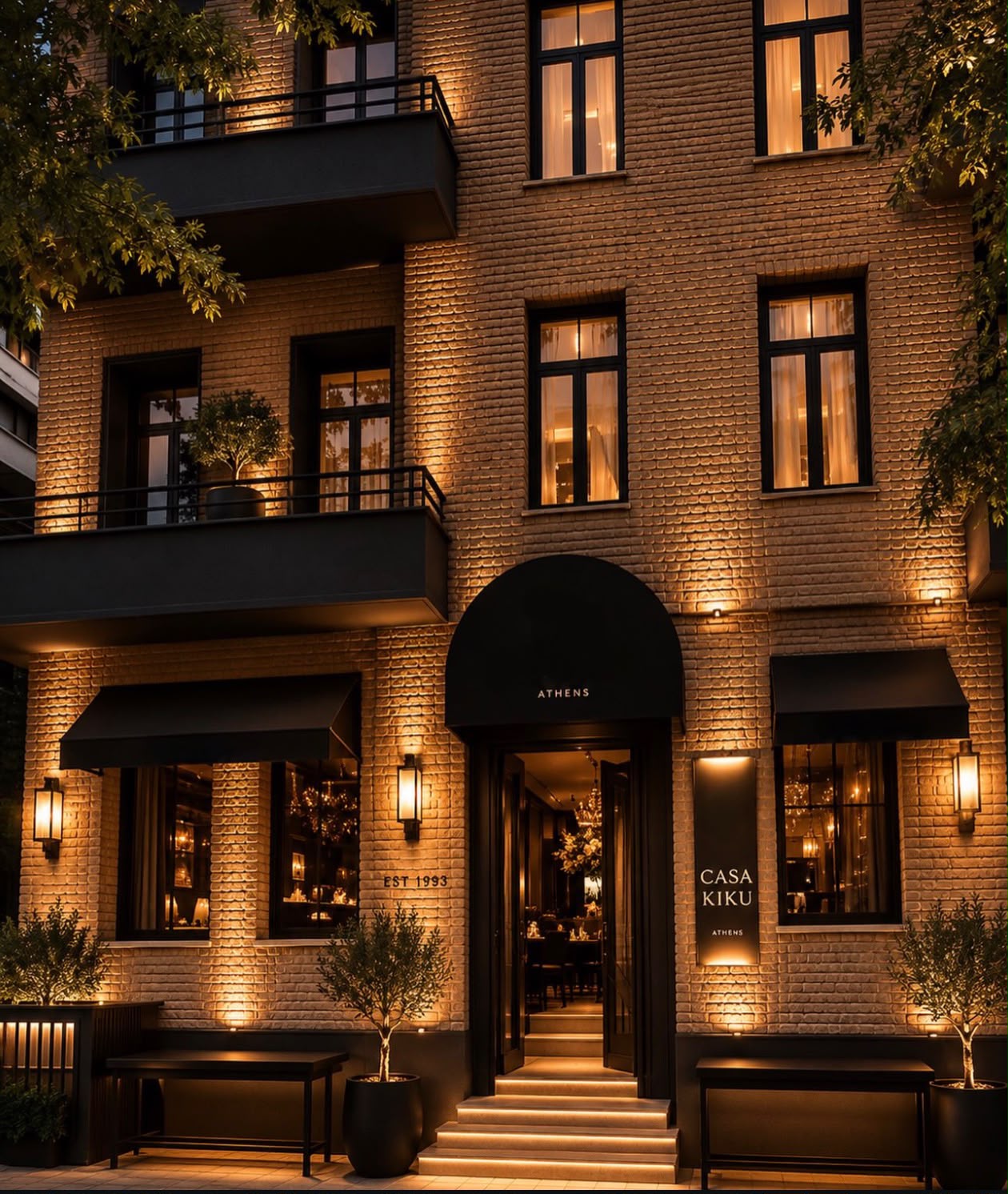 The brick facade of Casa Kiku at night, with warm lighting and the Casa Kiku Athens entrance