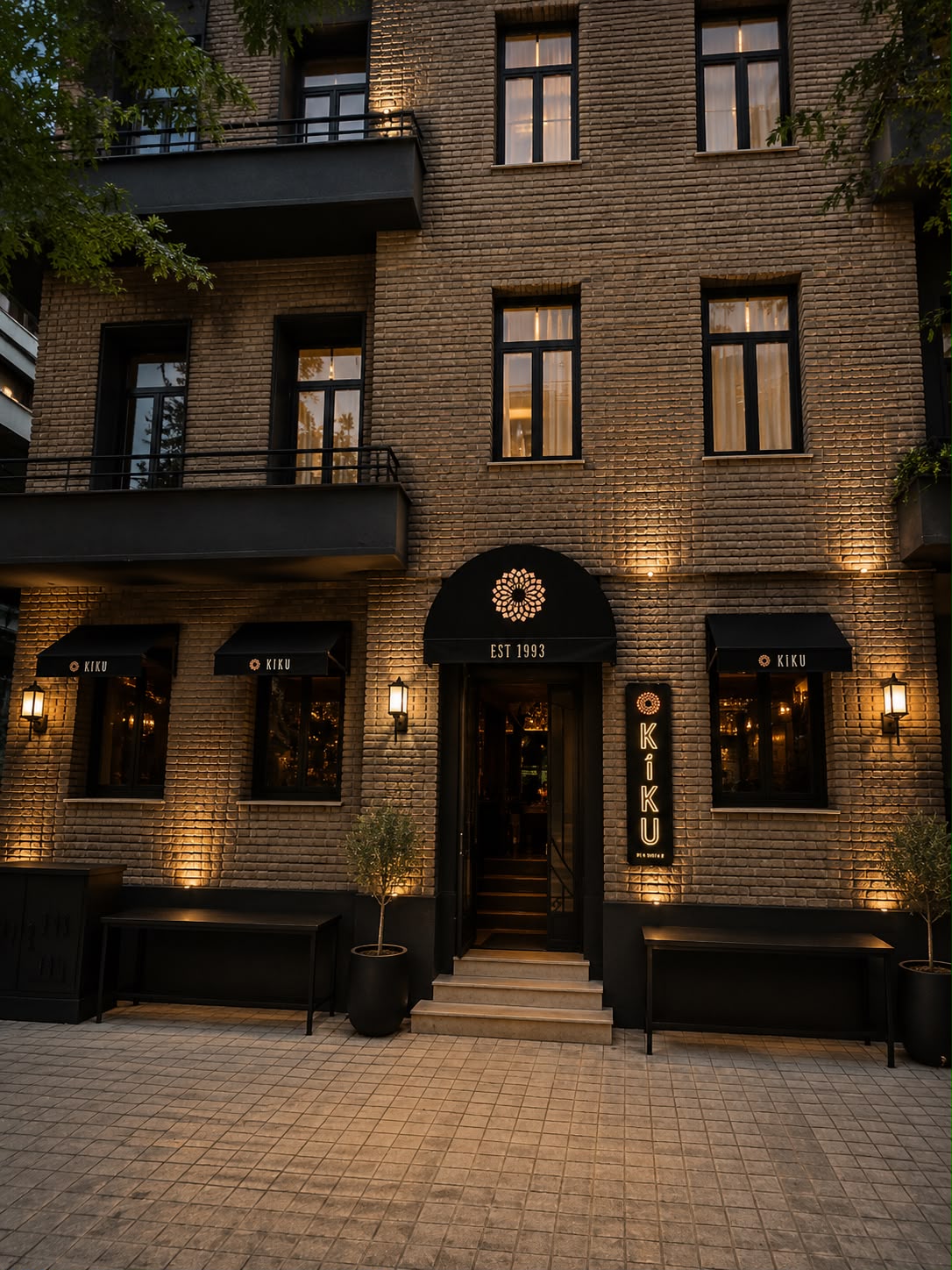 The lit brick facade of Casa Kiku in Kolonaki, with the Kiku sign and awnings, established 1993